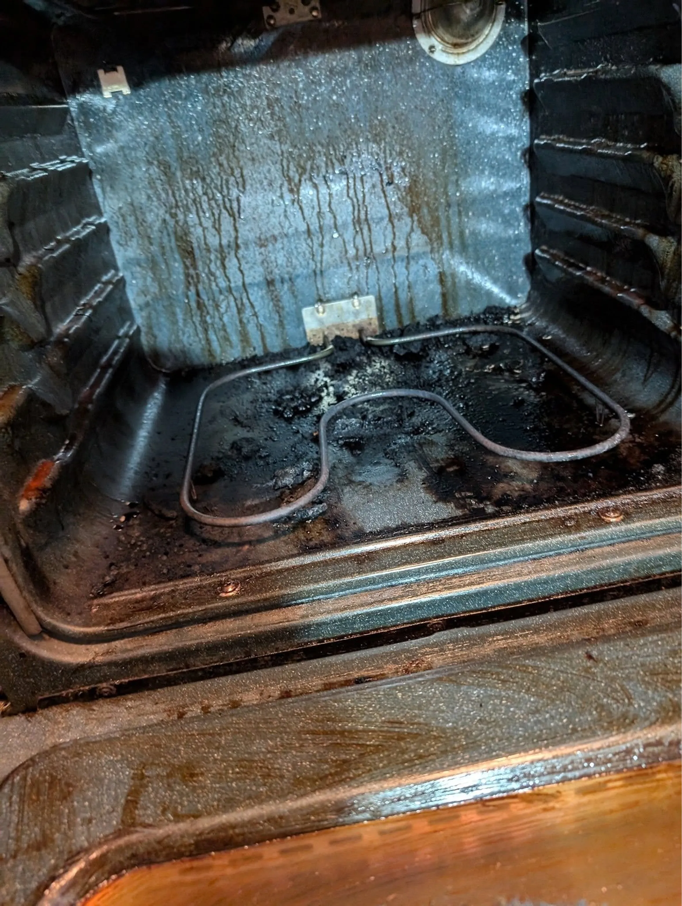 Oven interior coated in grease drips and burnt residue before cleaning