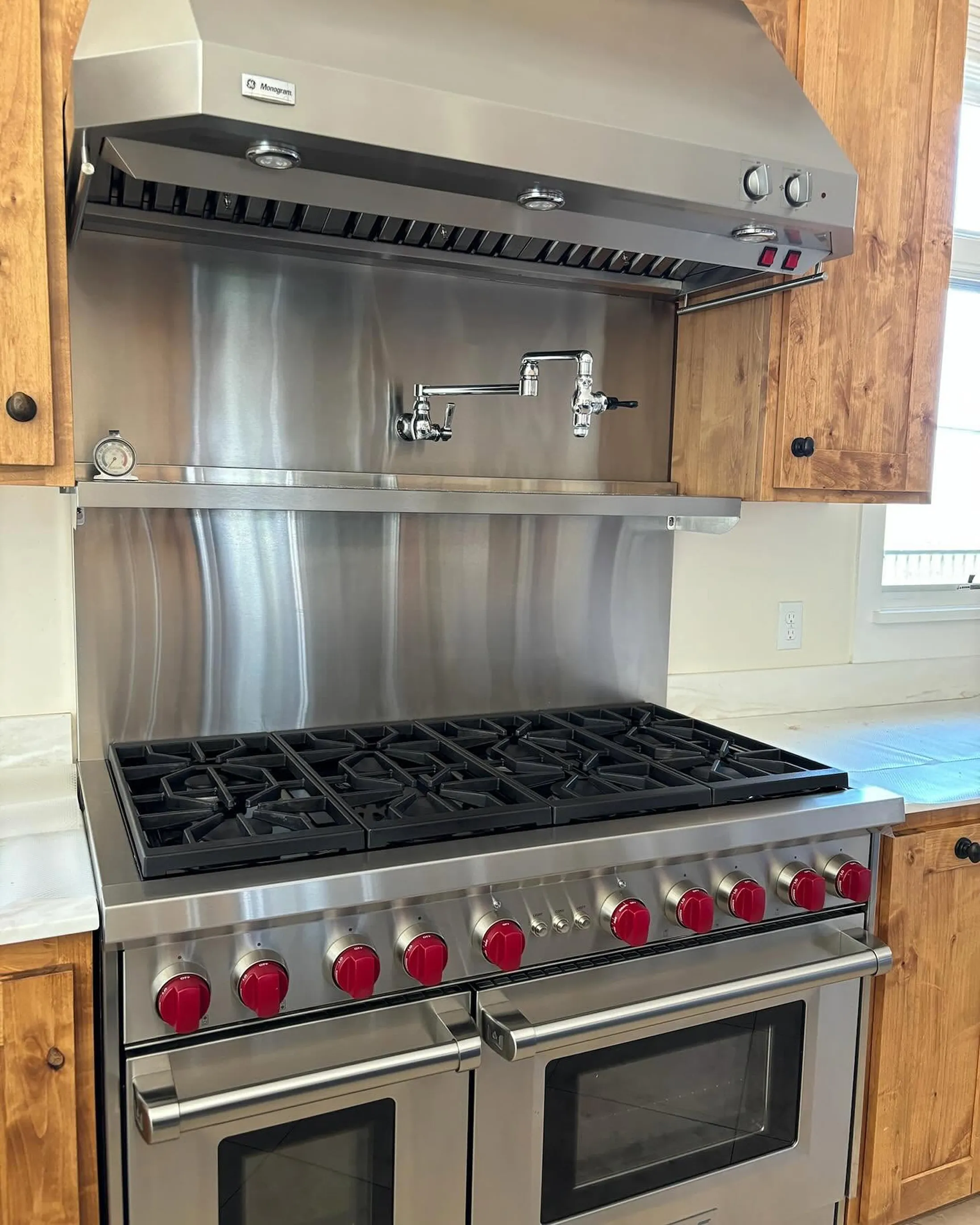 Large stainless steel range with red knobs, a pot filler, and a polished hood, clean after a visit from our team