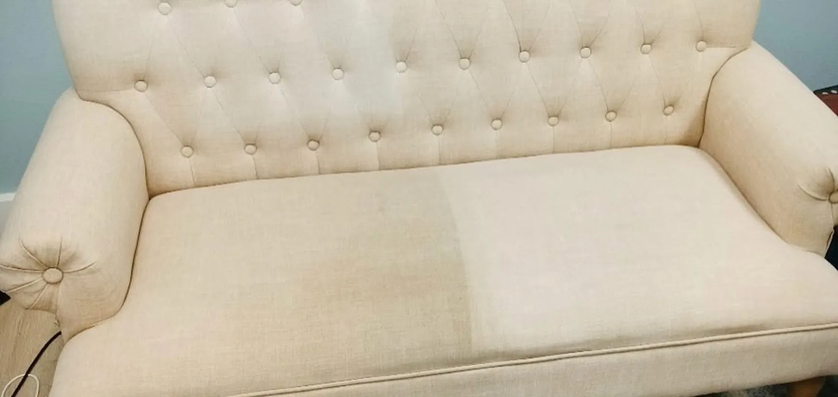 Cream tufted loveseat cleaned on the right half only, showing the difference against the dingy left half