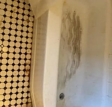 Shower wall with dark streaks and grime before cleaning