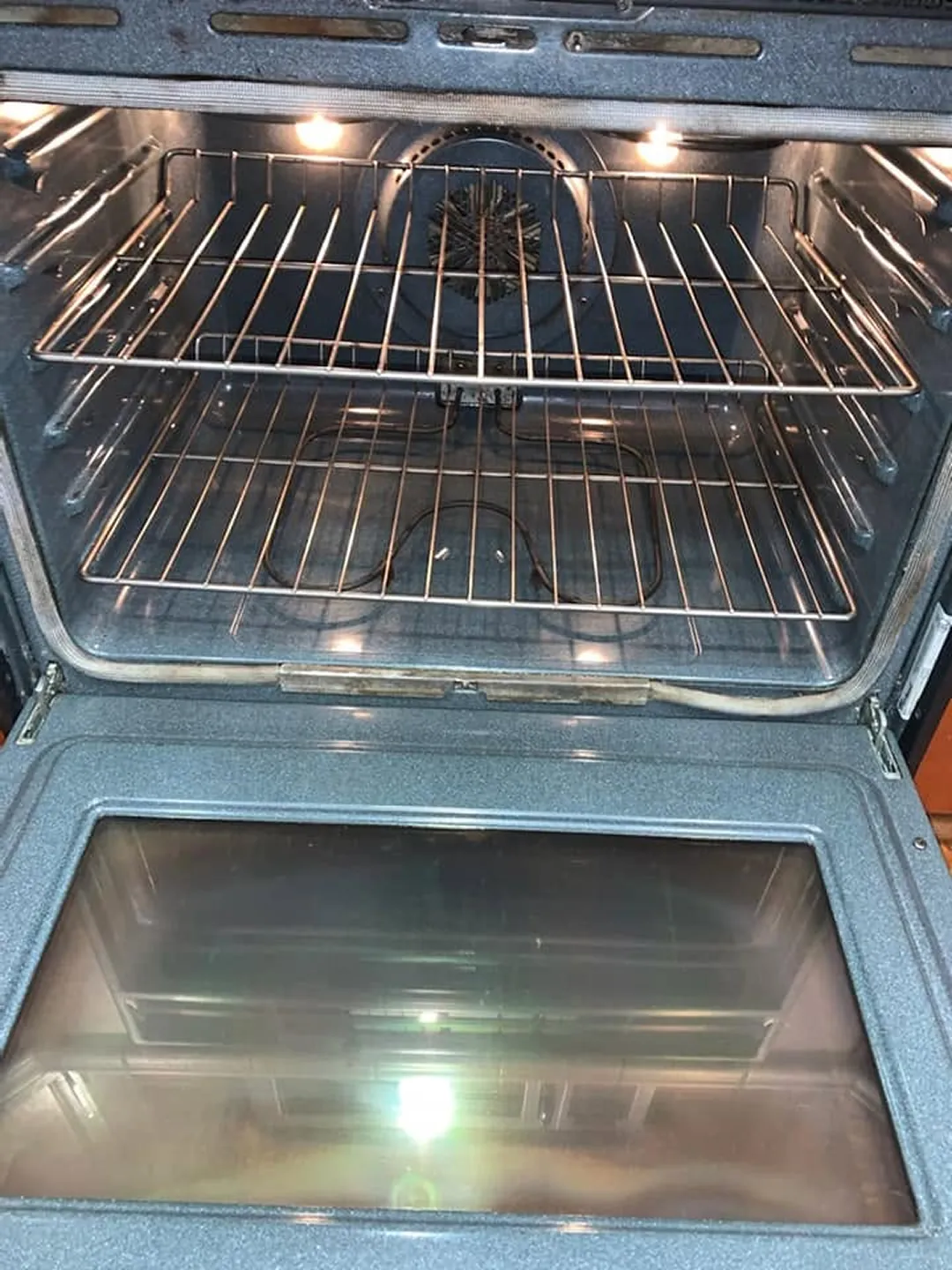 The same wall oven after cleaning, with shiny racks and a clear door