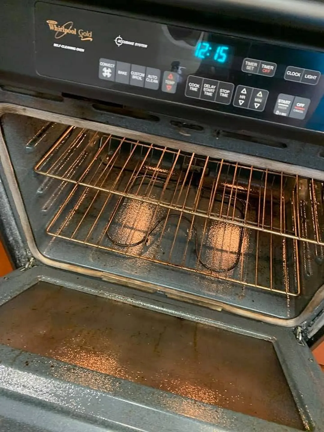 Wall oven with greasy racks and a stained door before cleaning